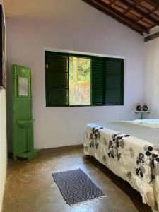 een slaapkamer met een bed, een raam en een tapijt bij Casa charmosa em condomínio arborizado in Nova Lima