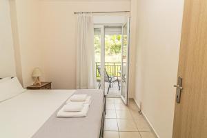 a bedroom with a bed and a door with a balcony at Sunday Mood in Nea Skioni