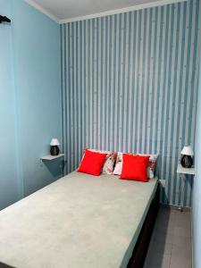 - une chambre avec un lit et 2 oreillers rouges dans l'établissement Ap beira-mar com wi-fi e garagem, à Mongaguá