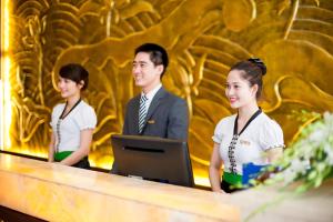 Een man en twee vrouwen aan een balie met een computer. bij Muong Thanh Luxury Can Tho Hotel in Can Tho