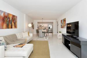 ein weißes Wohnzimmer mit einem weißen Sofa und einem TV in der Unterkunft SPECIAL Beautiful Modern Beach Condo in Miami Beach