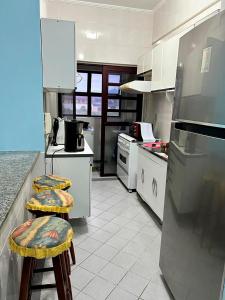 a kitchen with two stools in a kitchen with a refrigerator at Ap beira-mar com wi-fi e garagem in Mongaguá