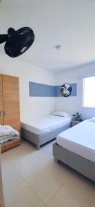 een slaapkamer met 2 bedden en een plafondventilator bij Cómodo apartamento cerca al mar. in Cartagena