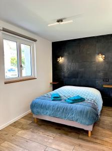 um quarto com uma cama com lençóis azuis e uma janela em L’Escale em Riquewihr