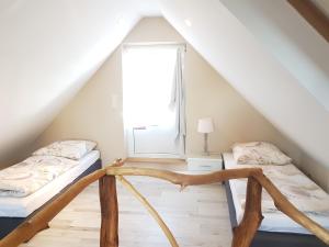 two beds in a attic room with a window at Ferienhaus am Rande des Müritz-Nationalparks in Kargow