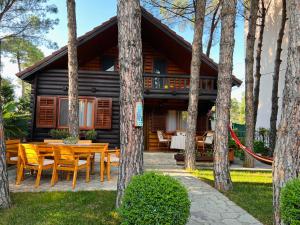 a log cabin in the woods with a table and chairs at Vila Lulebore in Velipojë