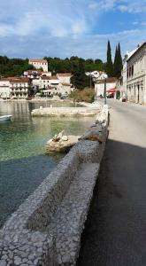 a stone wall next to a river next to a street at Apartments Korta in Račišće