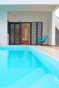 a blue swimming pool with a chair next to a house at Ofim Holidays in Ambohidratrimo