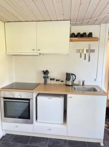 una pequeña cocina con armarios blancos y fregadero en Tiny House i storslået natur, en Frederikshavn