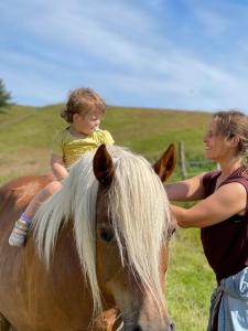 Una mujer y un niño sentados encima de un caballo en Tiny House i storslået natur en Frederikshavn