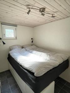 a large bed in a room with a ceiling at Tiny House i storslået natur in Frederikshavn