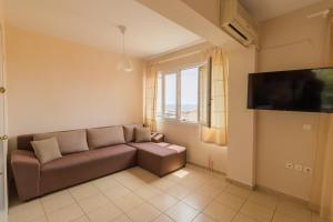a living room with a couch and a large window at Sunday Mood in Nea Skioni
