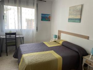 a bedroom with a bed and a table and a chair at Hostal Mediterraneo in Torre del Mar