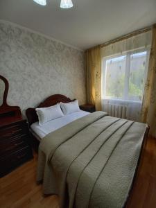 ein Schlafzimmer mit einem großen Bett und einem Fenster in der Unterkunft ОРАНЖЕВЫЙ МИР in Aqtöbe