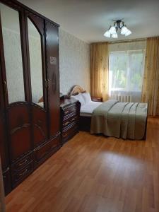 ein Schlafzimmer mit einem Bett, einer Kommode und einem Fenster in der Unterkunft ОРАНЖЕВЫЙ МИР in Aqtöbe