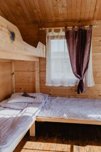 two beds in a log cabin with a window at Lawendowe Domki Mielno in Mielno