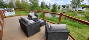 een terras met twee rieten stoelen en tafels erop bij Bluebell Luxury 2 Bedroom Lodge at Southview Holiday Park in Skegness