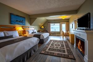 Habitación de hotel con 2 camas y chimenea en Sidney Waterfront Inn & Suites, en Sidney