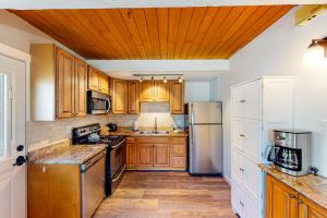 una cocina con armarios de madera y electrodomésticos de acero inoxidable en Shredders & Hikers Delight Upstairs en Vail