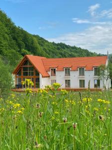 a white building with an orange roof and a field of flowers at Scrind 11 - Madleine Chalet in Cluj-Napoca