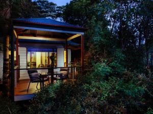 a house with a deck with a table and chairs at Lillypilly's Cottages & Day Spa in Maleny