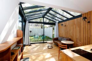uma sala de estar com um jardim de Inverno com um telhado de vidro em Le mazet des amants, cabane en bois avec jacuzzi privatif em Avignon