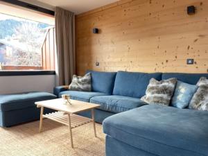 - un salon avec un canapé bleu et une table dans l'établissement Stijlvol 4-kamerappartement in Valmorel aan de piste, à Valmorel