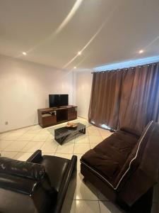 un soggiorno con un divano e una TV di Trilha do Mar 207 ad Arraial do Cabo