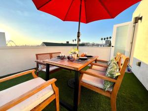 un tavolo e sedie con ombrellone rosso sul balcone di Luxury K-Town Dwelling with private rooftop deck. a Los Angeles