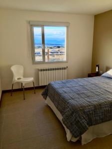 1 dormitorio con 1 cama, 1 silla y 1 ventana en Go Patagonia! en El Calafate