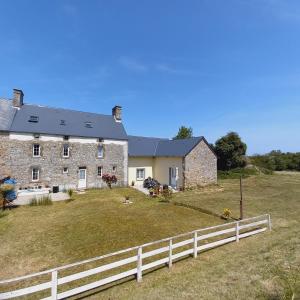 a large stone house with a white fence at L' Anpeg, gîte dans le Cotentin jusqu'à 8 personnes in Besneville
