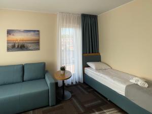 a bedroom with a bed and a couch and a window at ADANIA 1 in Grzybowo