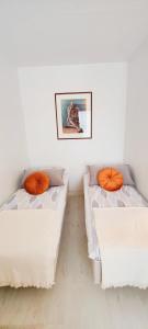 two beds in a room with orange pillows on them at Very quiet and well located apartment in Tammela, Tampere in Tampere