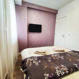 a bedroom with a bed and a tv on a wall at VIP Apartment in Jagodina