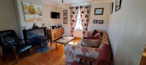 Patricia’s Country Cottage في سليغو: غرفة معيشة مع أريكة ومدفأة