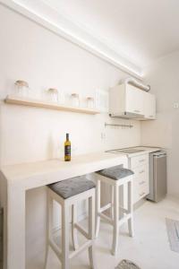 una cocina blanca con barra con taburetes y una botella de vino en The cozy nest, en La Canea