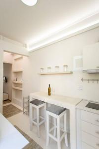 una cocina blanca con encimera y taburetes en The cozy nest, en La Canea