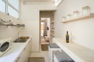 Una cocina blanca con fregadero y una barra con una botella de vino. en The cozy nest, en La Canea