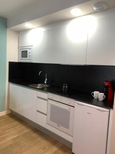 a kitchen with white cabinets and a sink at Joyel de la Ribera in Aranda de Duero