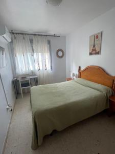 a bedroom with a large bed with a green blanket at Hostal Mediterraneo in Torre del Mar