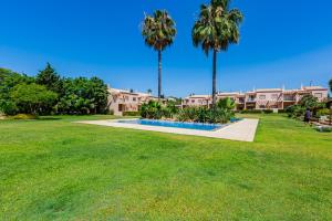 a park with palm trees and a building in the background at Casa Colina 2 in Albufeira