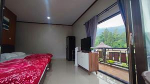 a bedroom with a bed and a large window at Gubuk Ndeso Homestay in Bromo