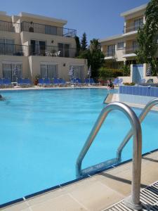 a large swimming pool with blue chairs in a hotel at Latchi Studio Apartment in Polis Chrysochous