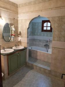 a bathroom with two sinks and a tub and a window at Agréable villa proche de la mer a Chott Meriem in Chott Meriem