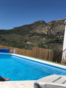 a swimming pool in front of a fence and a mountain at La Cordobesa in Priego de Córdoba