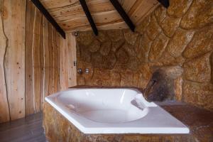 a bath tub in a room with a stone wall at Hotel & Spa Escondite de la Montaña in Sabana Redonda