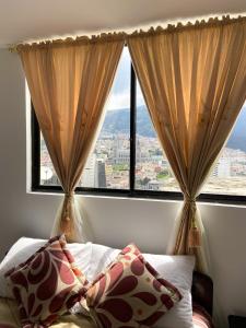 a bedroom with a bed and two large windows at Hostal La Terraza - Roof Terrace Overlooking The North and Historic Centre in Quito +56 photos