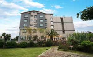 a large building in the middle of a yard at Seongsan Aqua Beach Hotel in Seogwipo