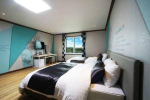 a bedroom with a large bed and a large window at Seongsan Aqua Beach Hotel in Seogwipo +22 photos
