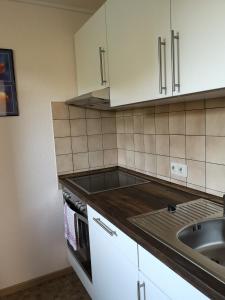 eine Küche mit weißen Schränken und einem Waschbecken in der Unterkunft Ferienwohnung Hermann in Bovenden